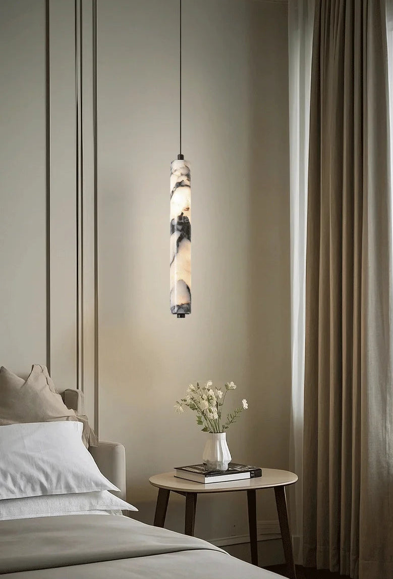 Pendant light fixture in a bedroom setting with a bed and side table.